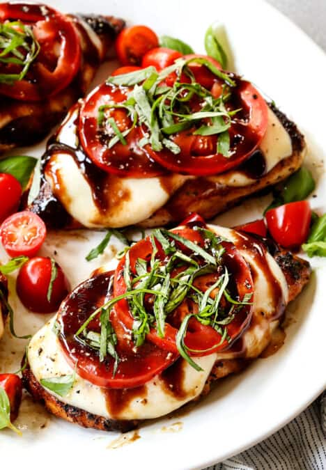up close of chicken caprese recipe being served on a white plate with mozzarella, tomatoes, basil and balsamic reduction (balsamic glaze)