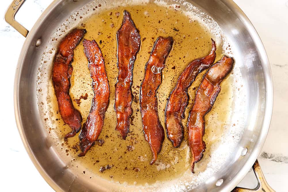 showing how to make bacon pasta by cooking bacon in a large stainless steel skillet