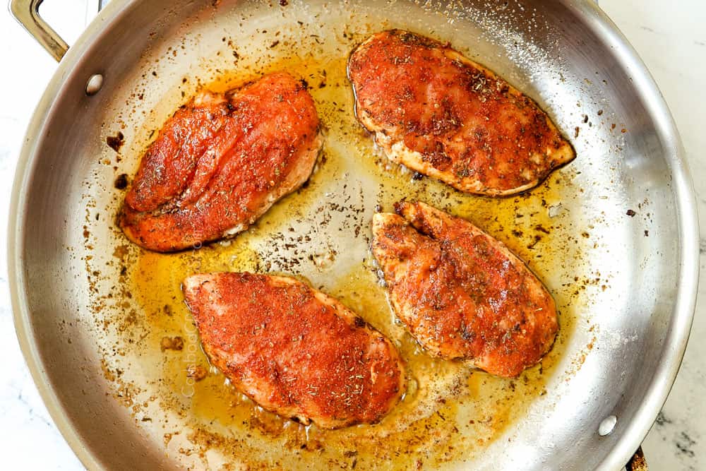 showing how to make blackened chicken recipe by adding seasoned chicken to a skillet with butter
