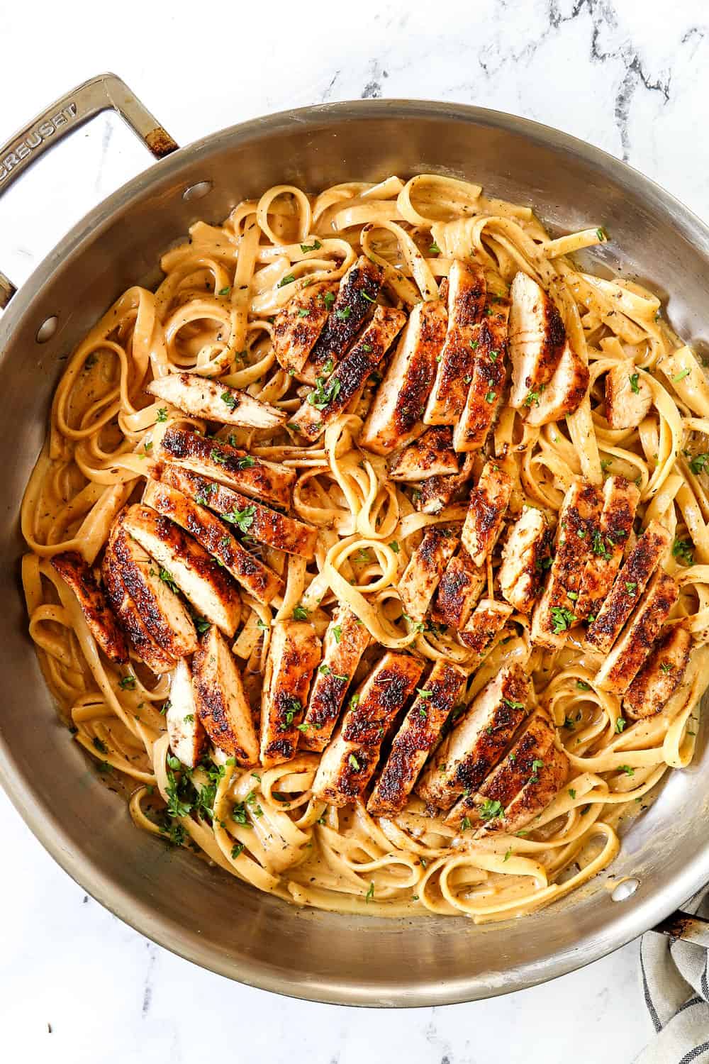 showing how to serve blackened chicken by adding chicken to blackened chicken alfredo