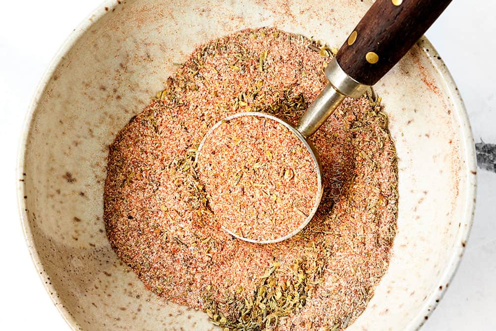 showing how to make blackened chicken recipe by whisking smoked paprika, onion powder, garlic powder, thyme, cayenne pepper, pepper and salt together in a bowl to make blackening seasoning blend