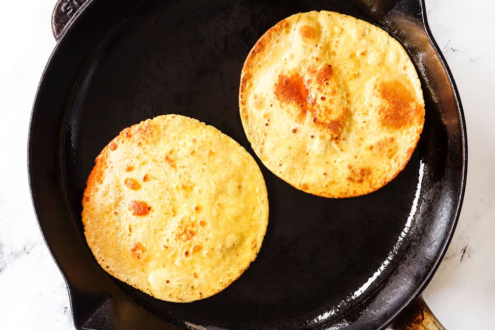 showing how to make huevos rancheros recipe by pan frying corn tortillas until golden