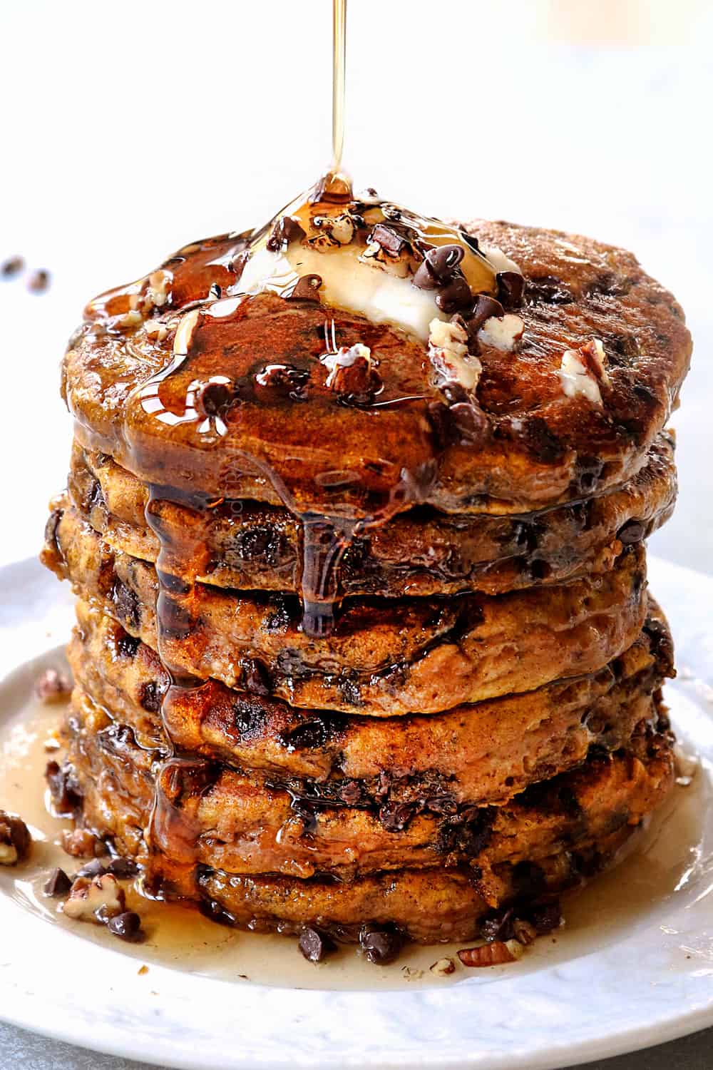 pouring syrup over a stack of pumpkin pancake recipe with chocolate chips