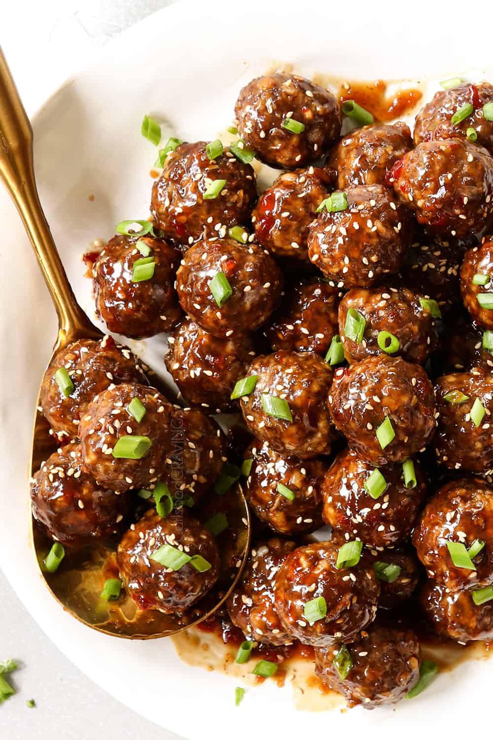 top view of teriyaki meatballs garnished by green onions on platter