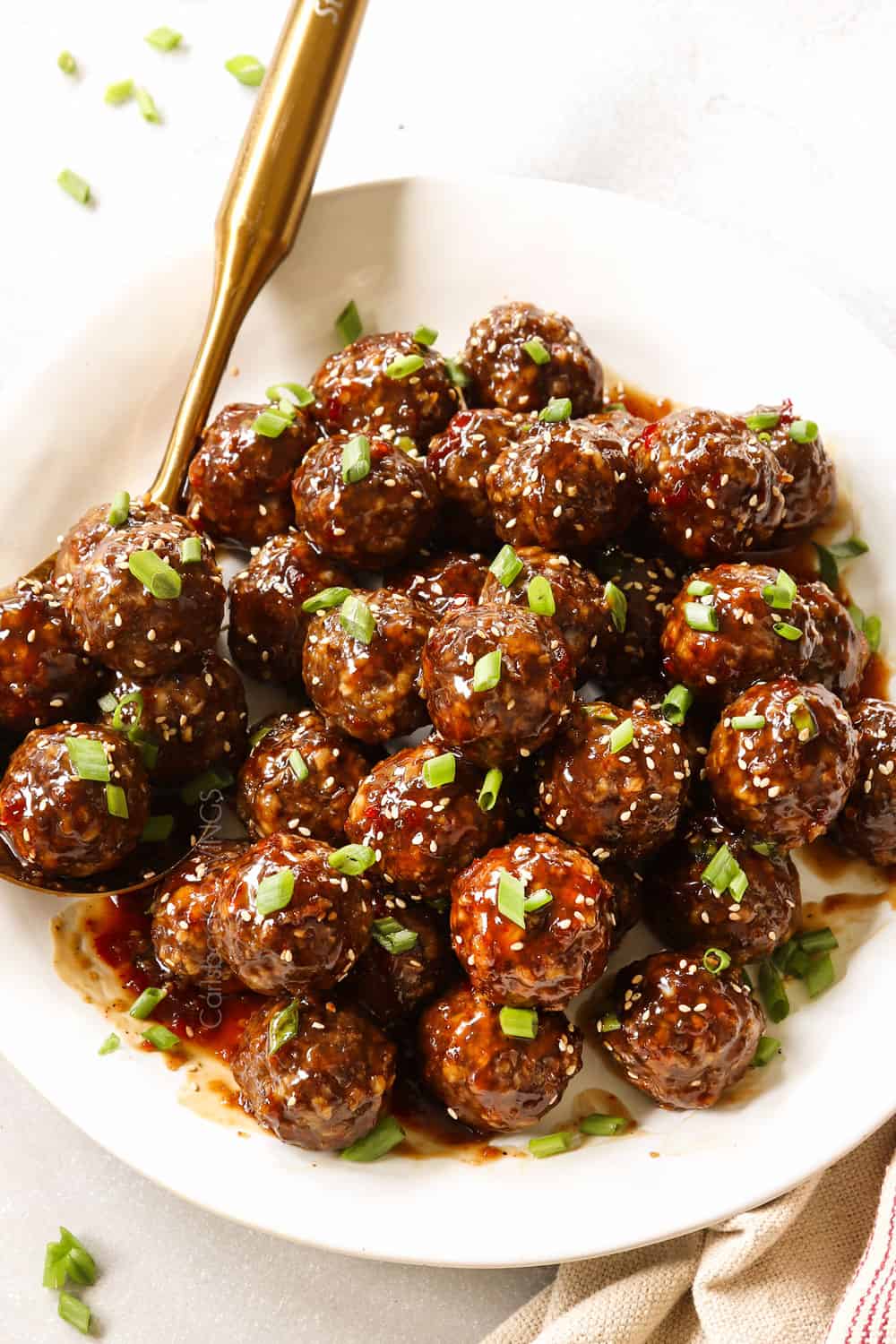 teriyaki meatballs on a white platter garnished by green onions