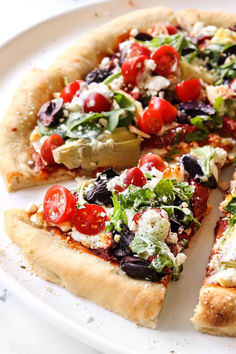 a slice of Greek pizza with Kalamata olives, feta, artichokes and tomatoes