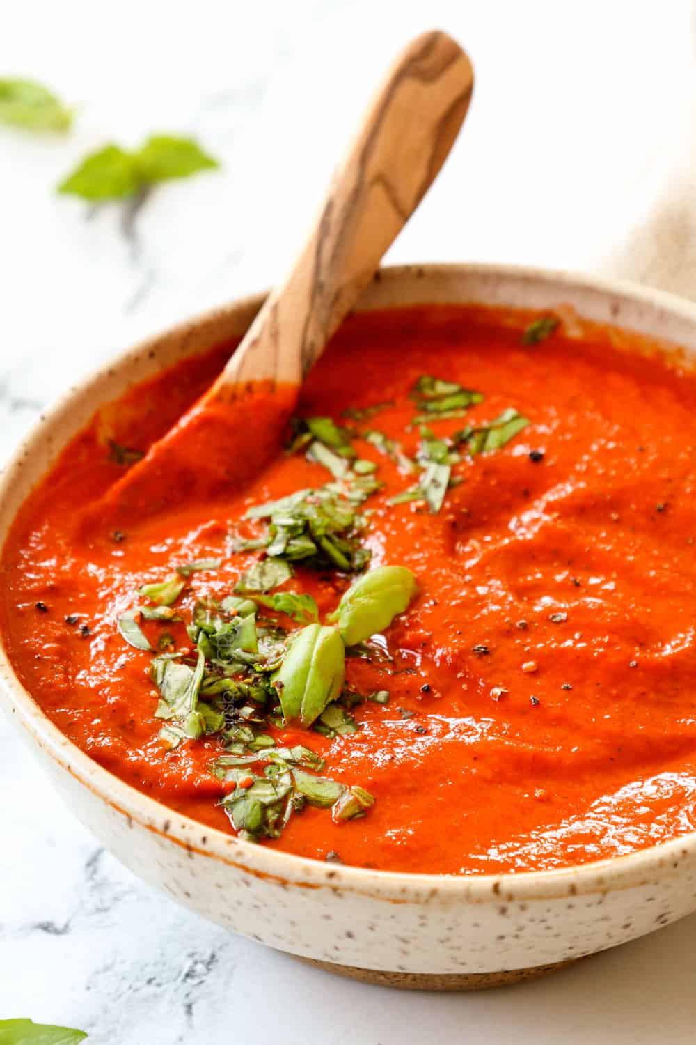 a bowl of roasted red pepper sauce garnished by basil