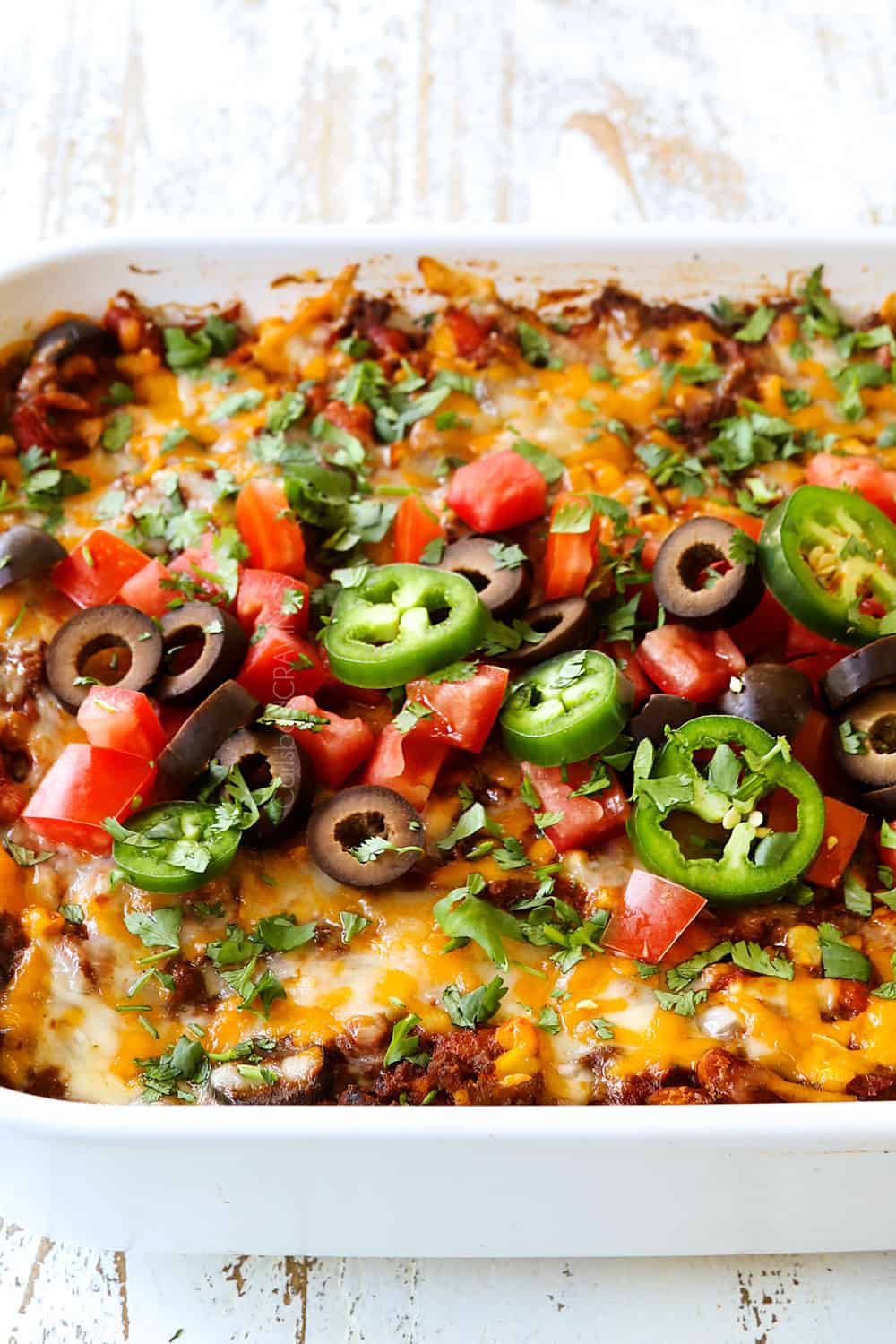 side view of enchilada casserole recipe garnished with tomatoes and jalapenos