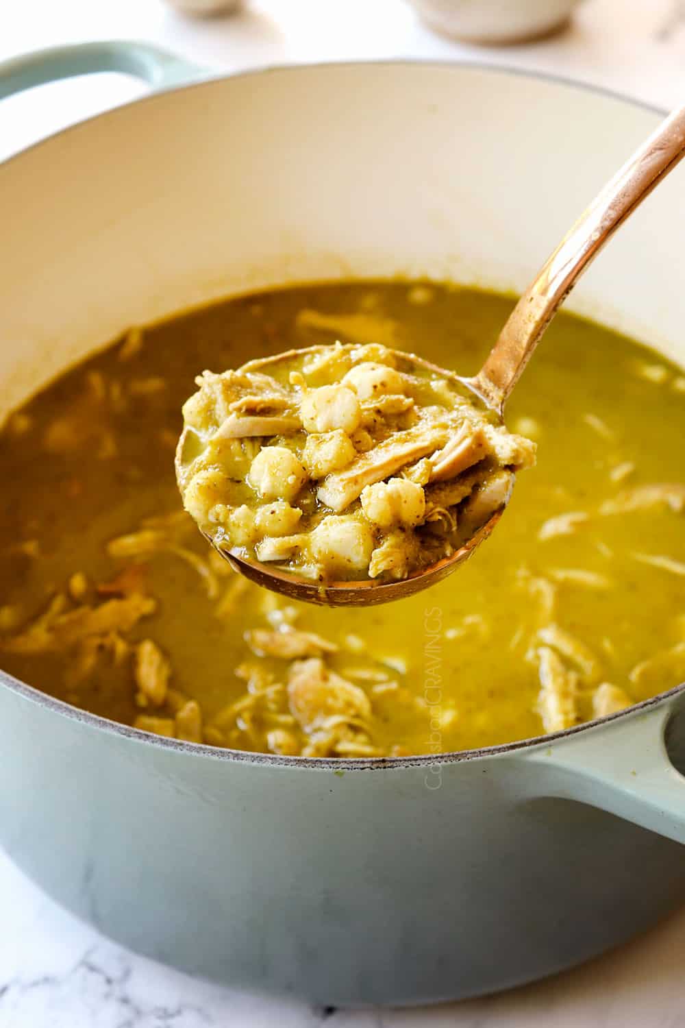 up close of a ladle of pozole verde (posole) with chicken