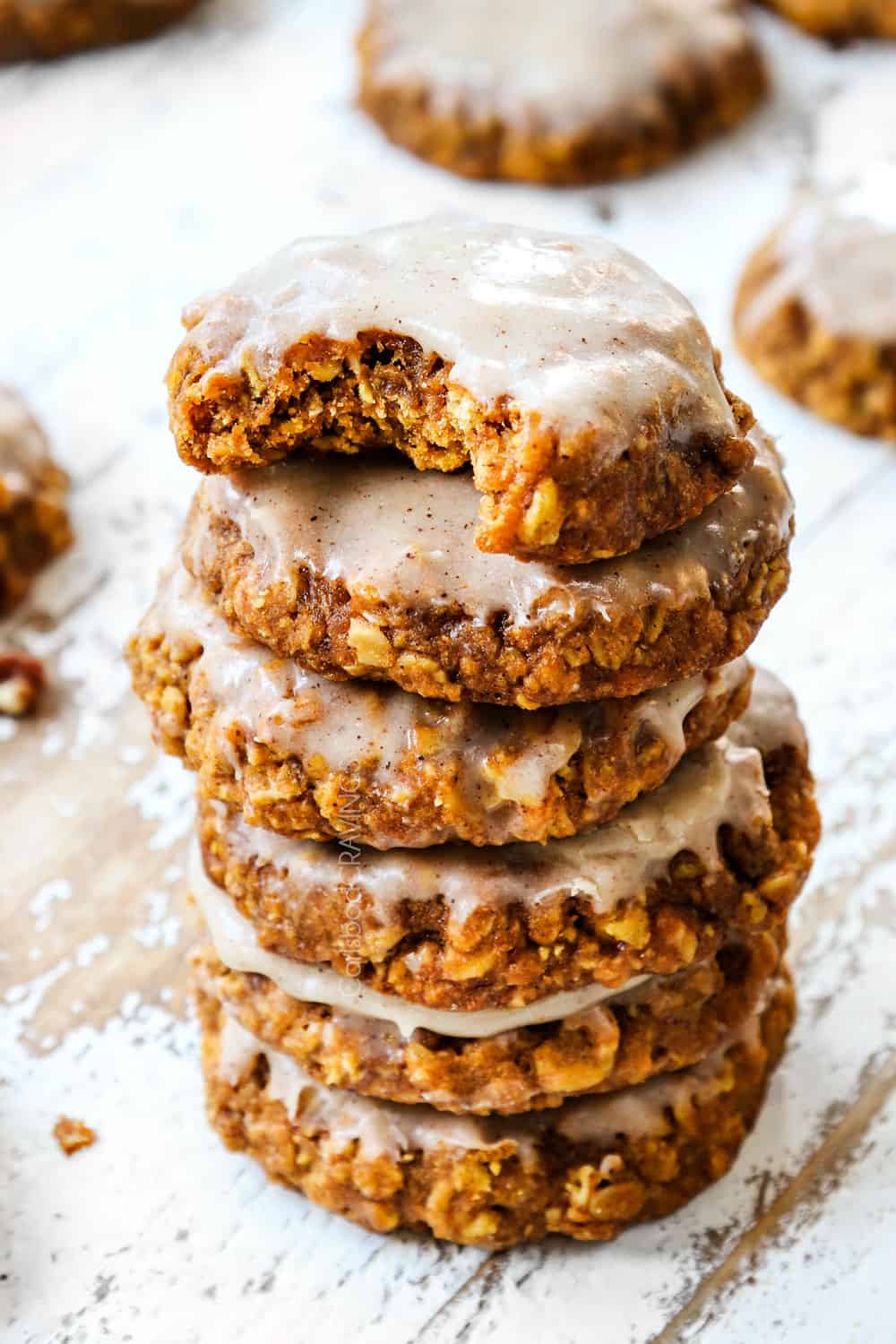 a stack of pumpkin oatmeal cookies with icing with a bite out of a cookie