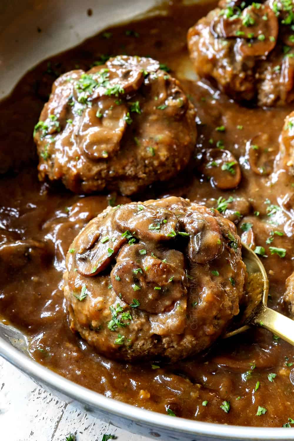 up close of a spoon picking up Salisbury Steak recipe showing how juicy the patties are