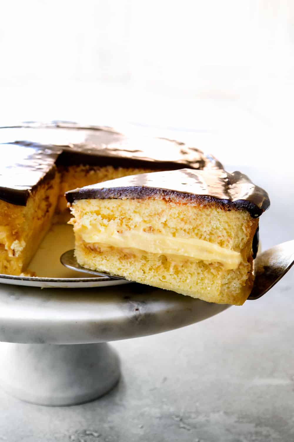 showing how to serve Boston Cream Pie by pulling a slice away from the cake