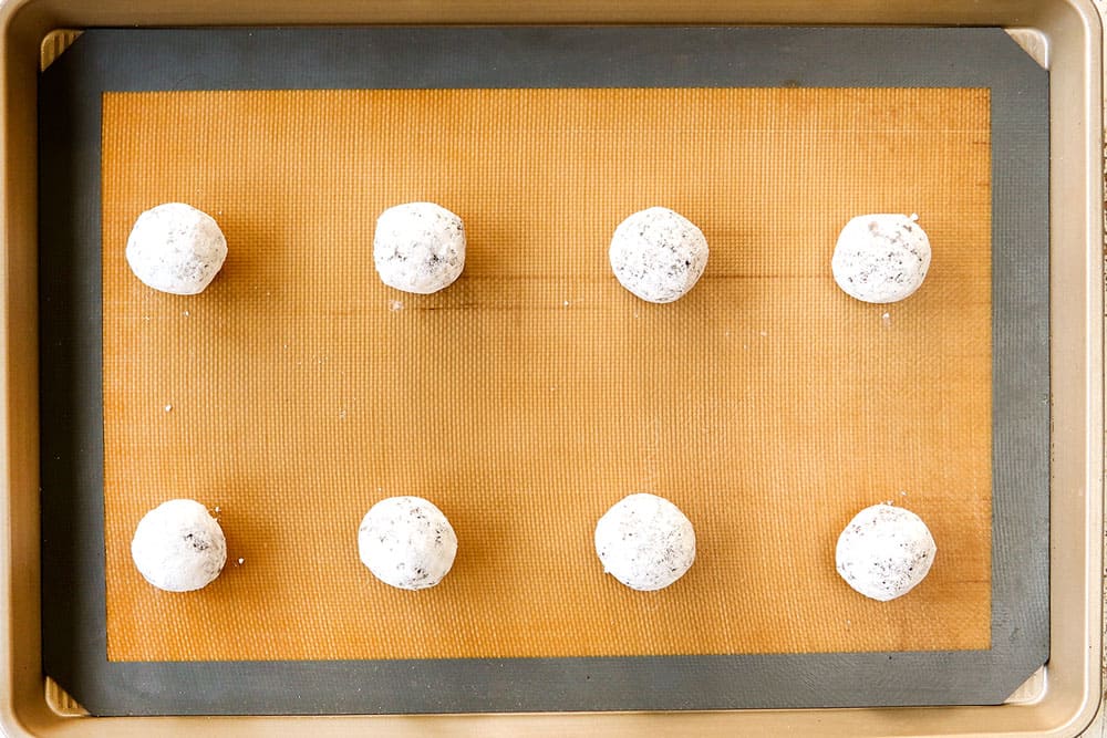 showing how to make chocolate crinkle cookies by adding the cookie balls to a baking sheet to bake