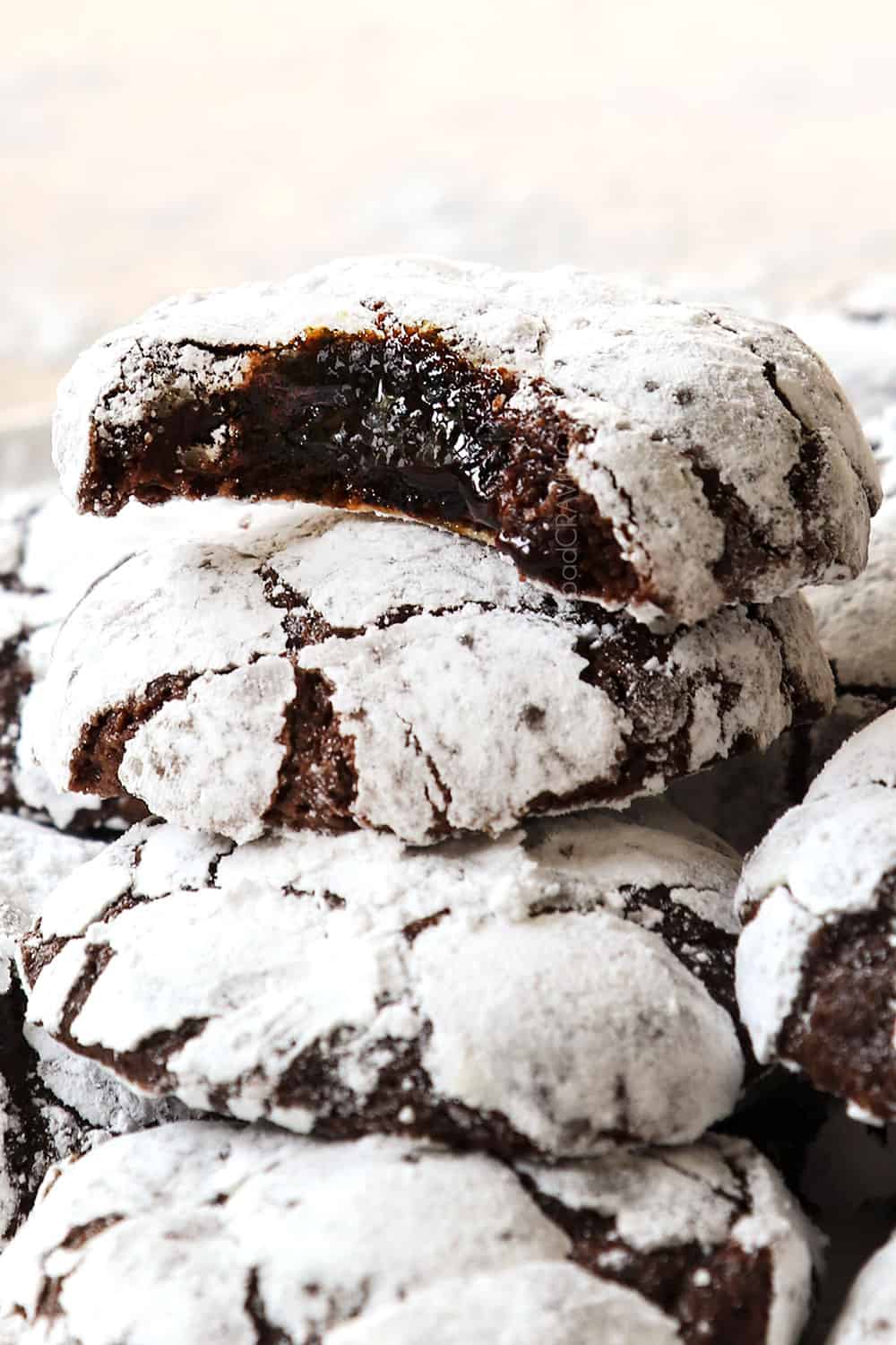 up close of chocolate crinkle cookies with a bite out of them showing how fudgy they are