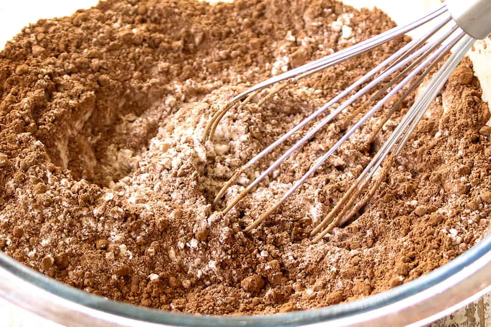 showing how to make chocolate crinkle cookie recipe by whisking the flour, baking powder and cocoa powder together in a bowl