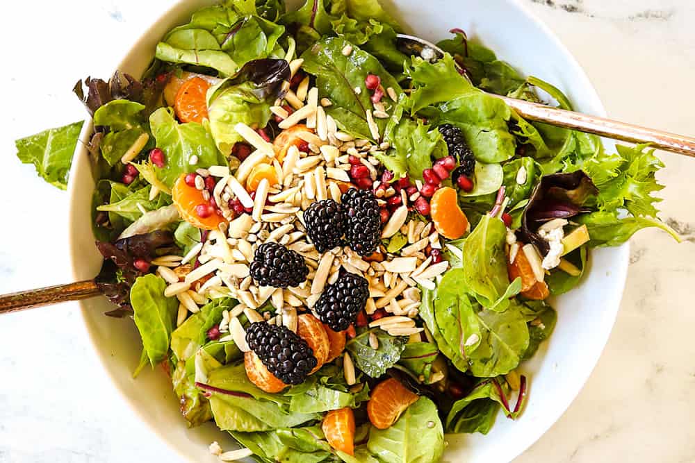 how to make Mandarin Orange Salad by tossing mandarins, almonds, pomegranate seeds and salad spring mix