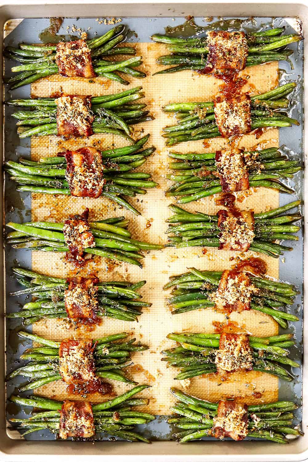 top view of bacon wrapped green beans on a baking sheet with rosemary