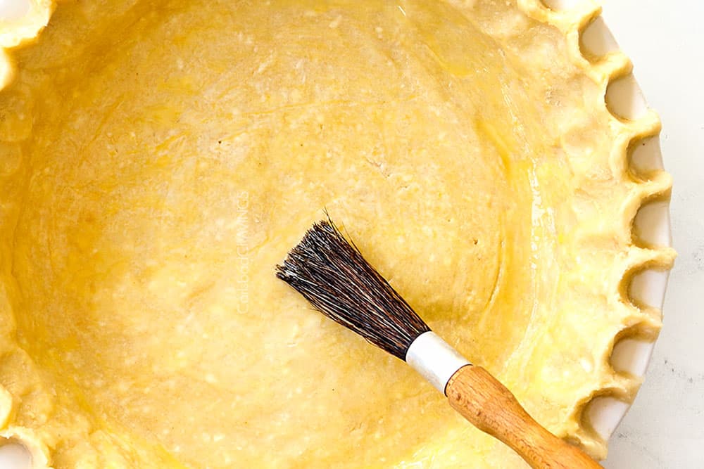showing how to make Dutch apple pie recipe (Apple Crumble Pie) by brushing pie crust with egg wash