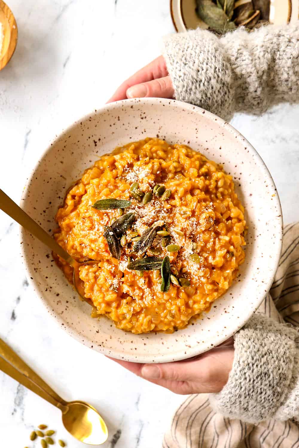 a bowl of pumpkin risotto recipe being held by two hands