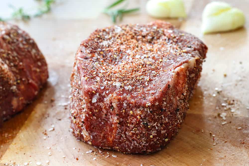 showing how to cook filet mignon by seasoning with kosher salt and pepper and letting it rest on a cutting board