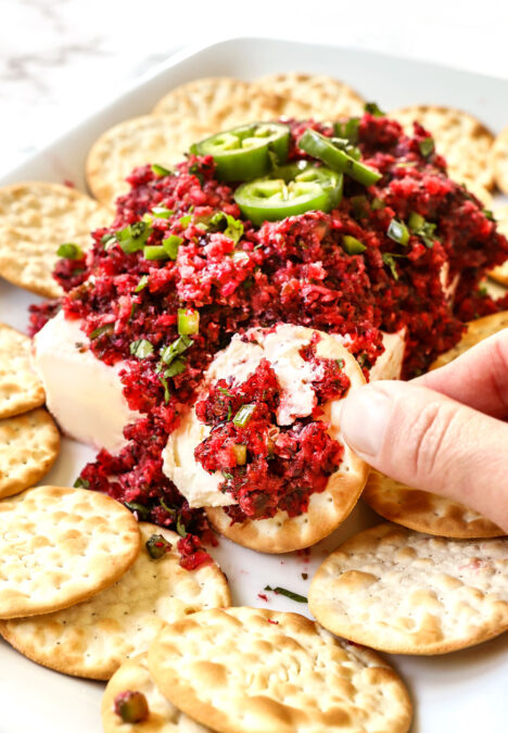scooping up cranberry salsa with a cracker