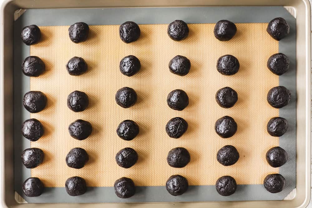 showing how to make Oreo Truffle recipe by adding Oreo balls to a baking sheet to freeze before dipping