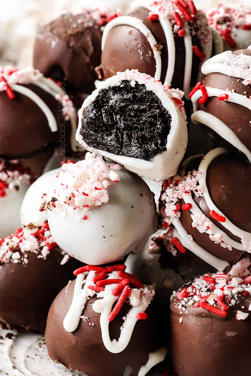 up close of oreo truffle balls recipe with crushed candy canes with a bite taken out of one of the truffles