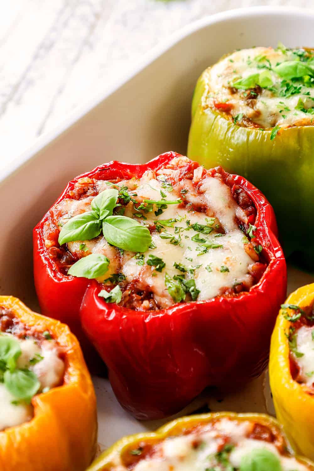 up close of stuffed bell peppers garnished with parsley in a baking dish