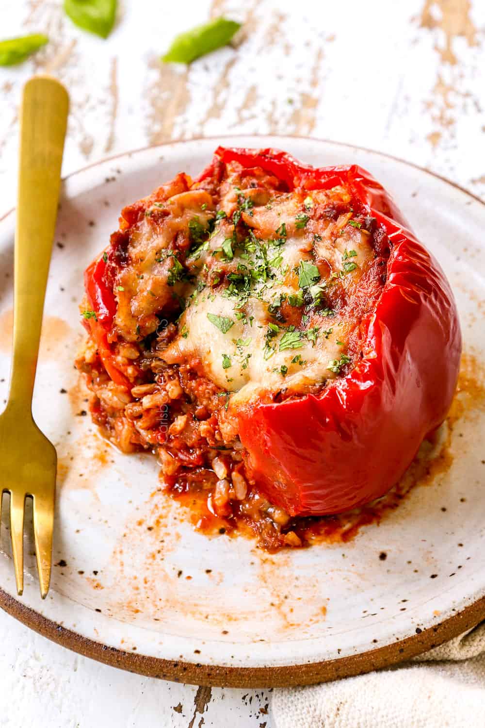 stuffed bell pepper on a plate with a bite take out so you can see the Italian sausage and rice filling