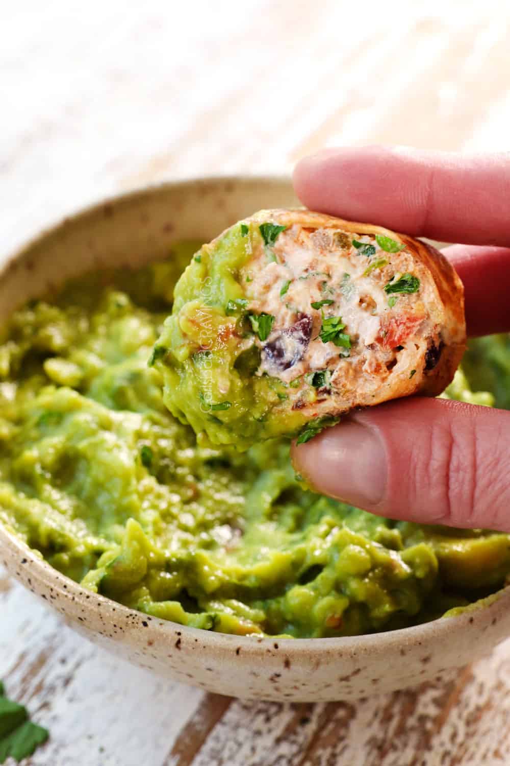 showing how to serve Mexican pinwheel recipe by dipping into guacamole