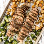 top view of balsamic roasted pork tenderloin sliced on a baking sheet oven roasted with potatoes and broccoli
