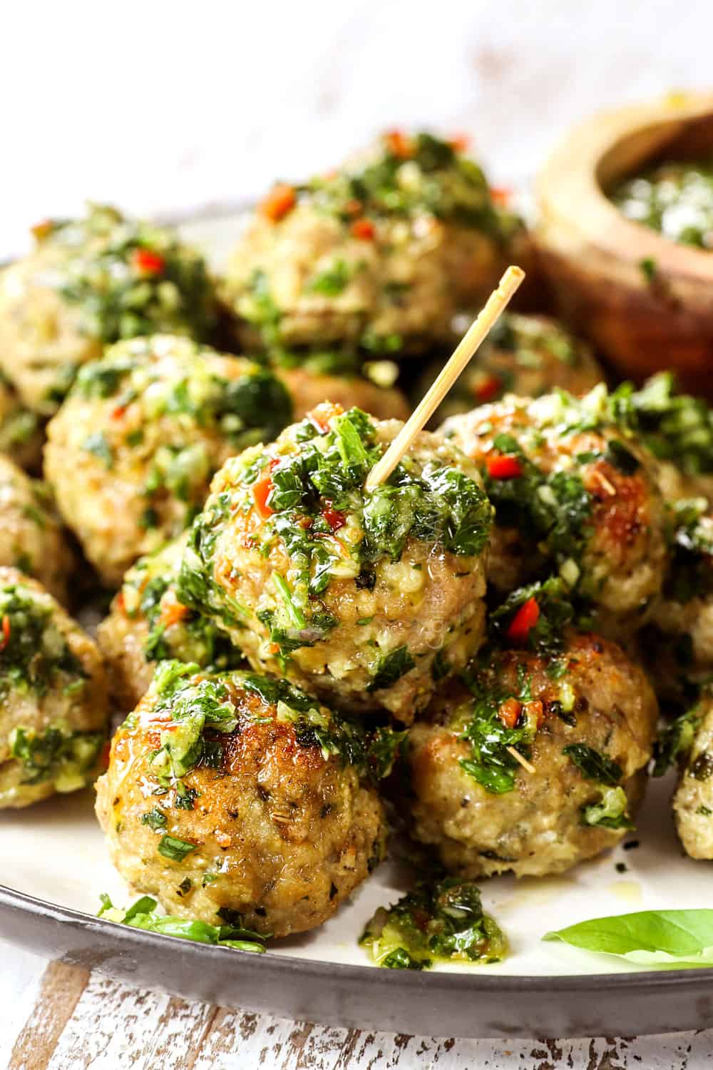showing how to serve chimichurri recipe by spooning it over meatballs