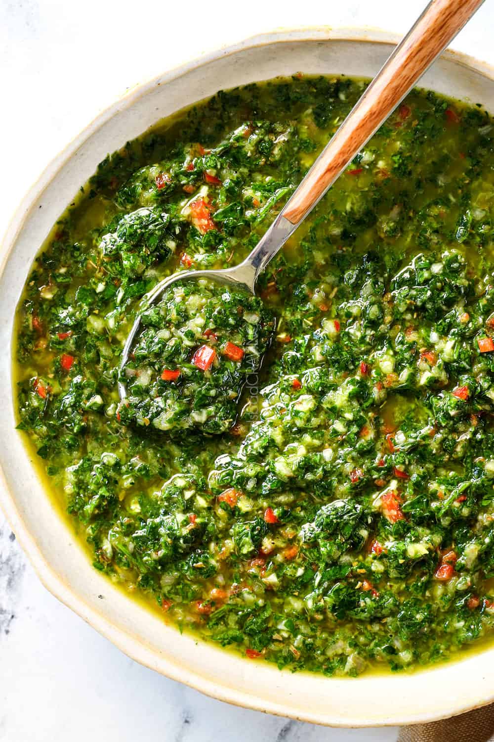 top view of the best chimichurri sauce recipe with parsley, oregano, red chili flakes, garlic and olive oil