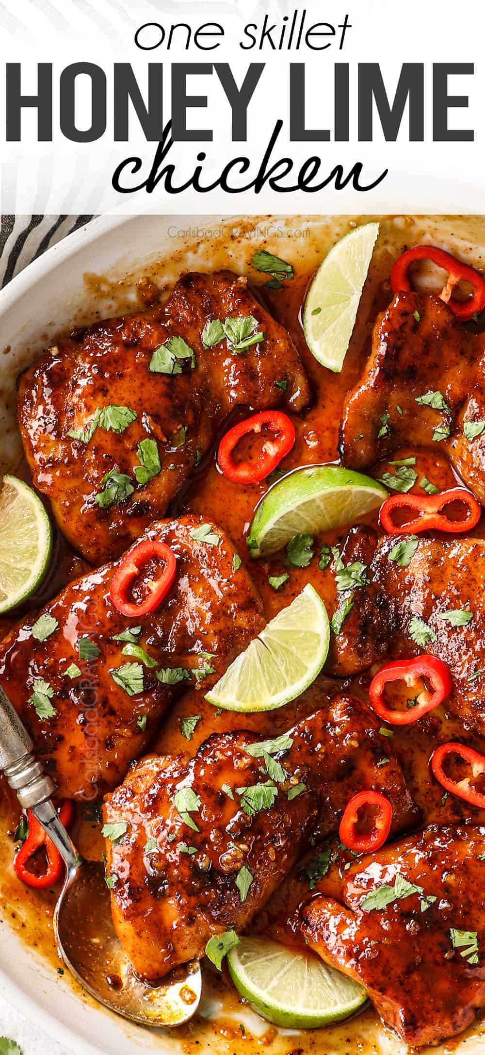 top view of honey lime chicken thighs in a skillet garnished with limes and chilies