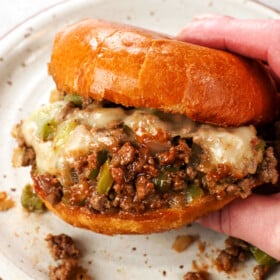 a hand holding Philly Cheesesteak Sloppy Joe showing the melted cheese and saucy filling