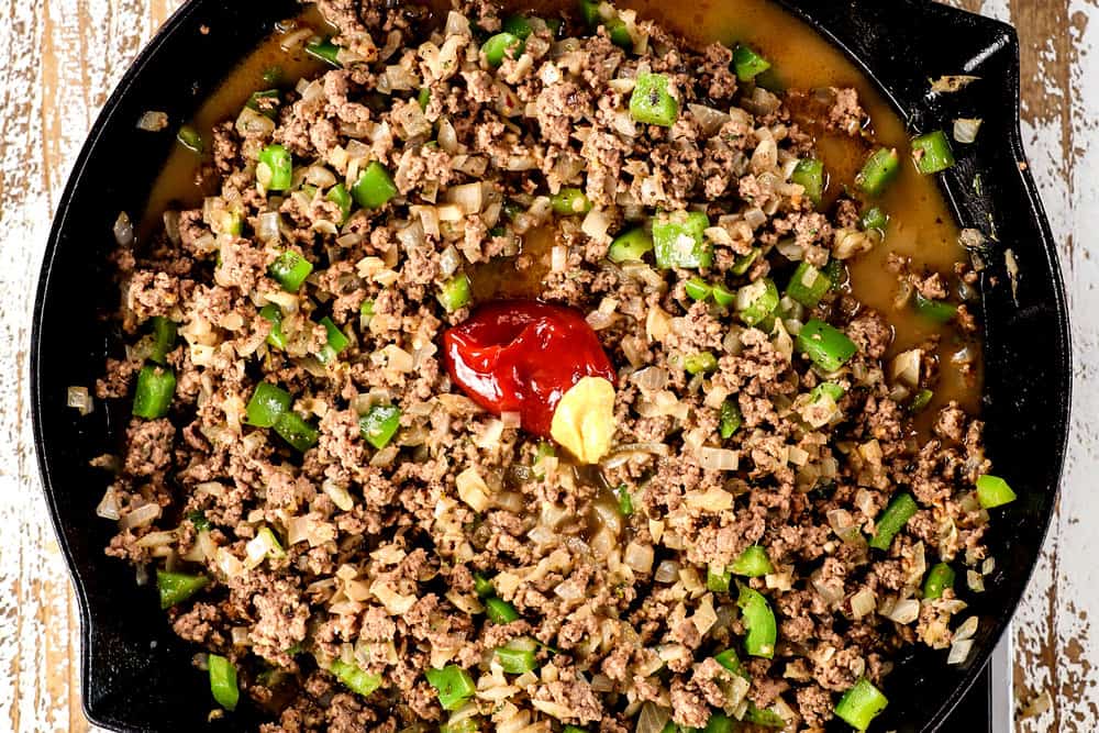 showing how to make Philly Cheesesteak Sloppy Joes by adding Worcestershire, ketchup, beef broth and seasonings to the meat mixture  
