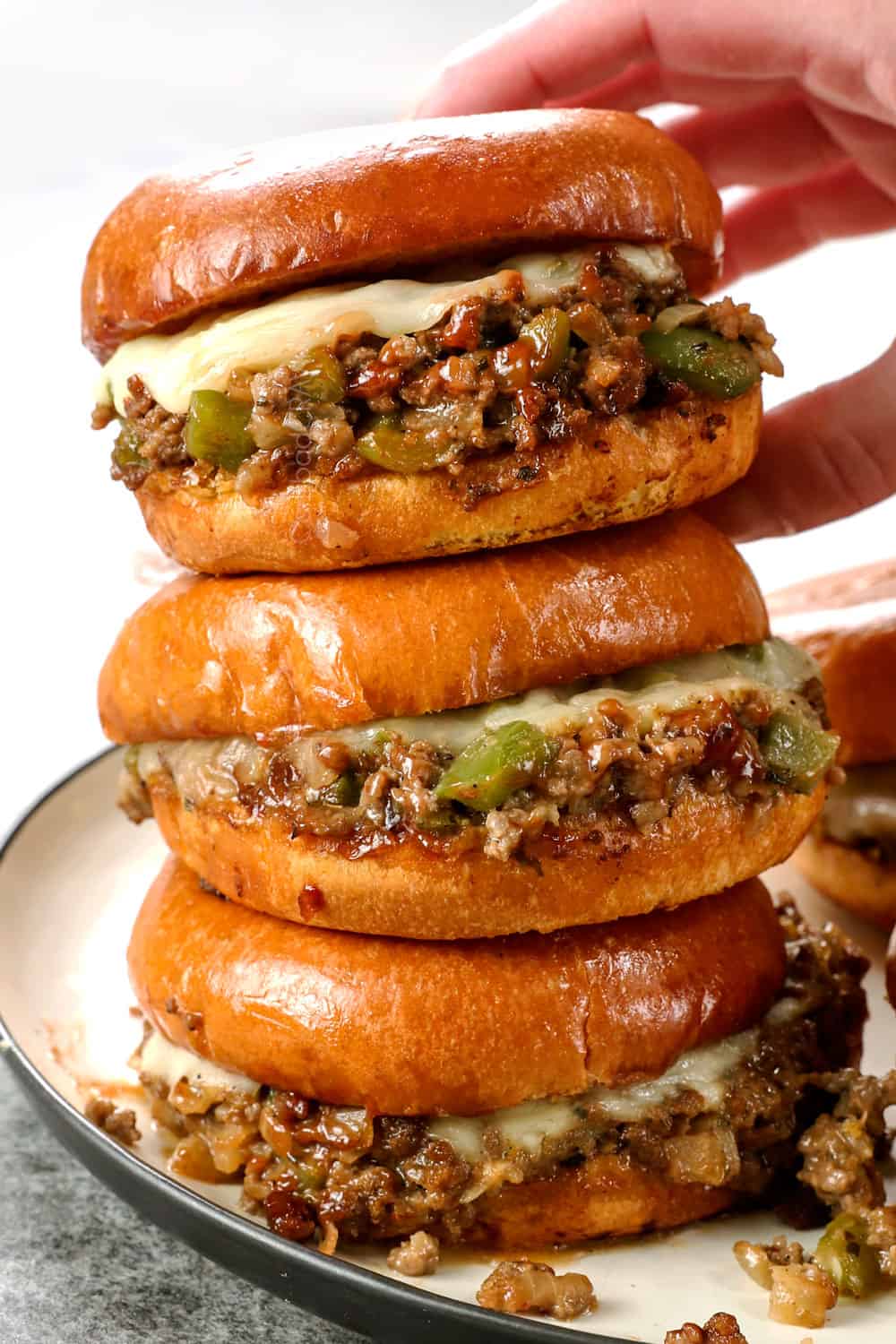 a stack of Philly Cheesesteak Sloppy Joes with provolone cheese in toasted brioche buns