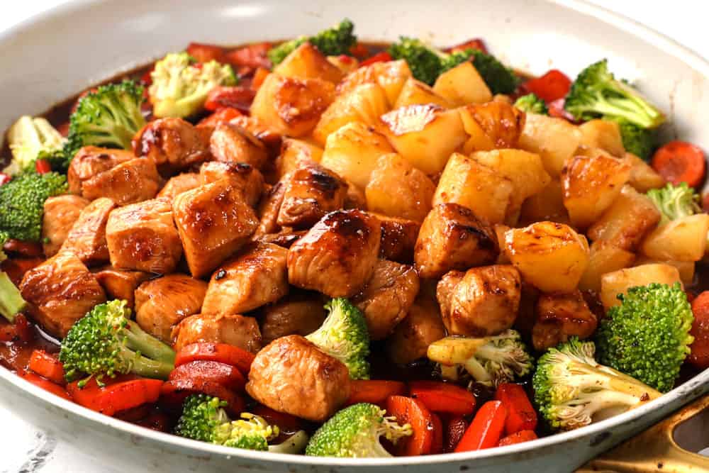 showing how to make healthy chicken teriyaki stir fry recipe by adding chicken, broccoli, carrots, pineapple and teriyaki sauce to a skillet