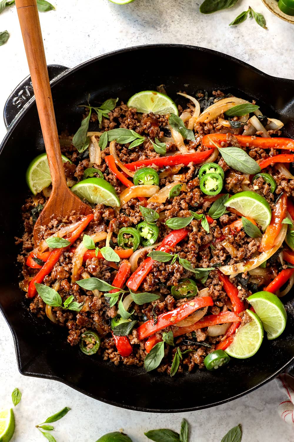 showing how to make Thai Basil Beef (pad krapow) by garnishing with fresh limes and Thai basil
