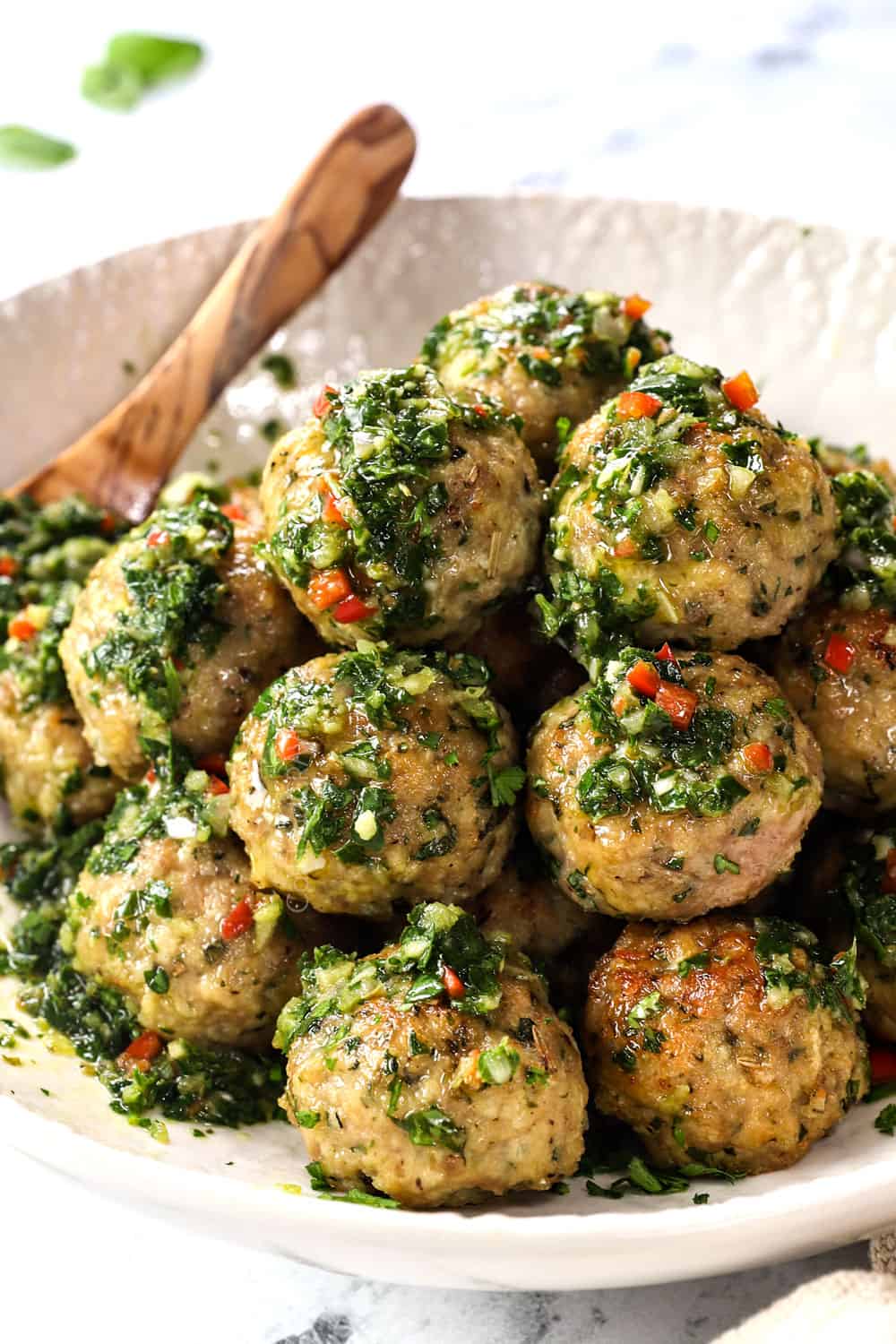 showing how to serve ground turkey meatballs by topping with chimichurri