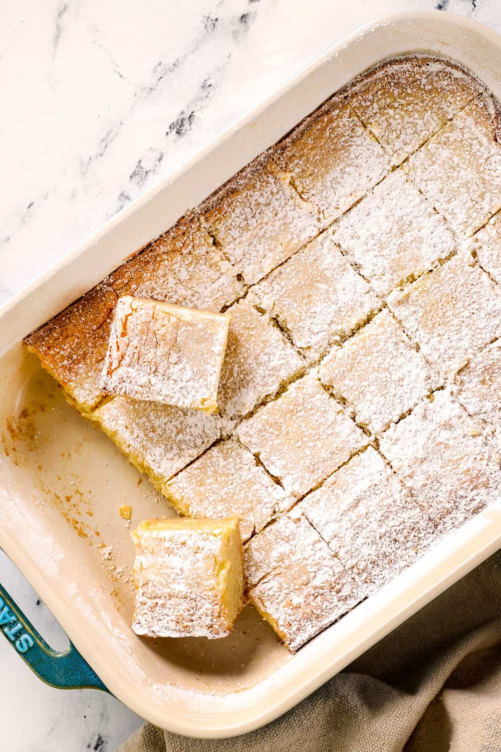top view of a Gooey Butter Cake recipe sliced into squares dusted with powdered sugar