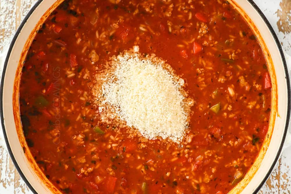 showing how to make stuffed pepper soup by stirring Parmesan into the cooked soup