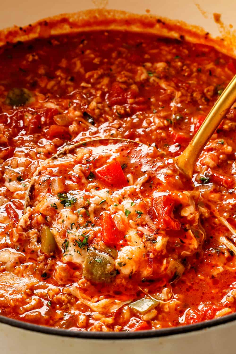 a ladle of stuffed pepper soup recipe with red and green bell peppers, Italian sausage and rice