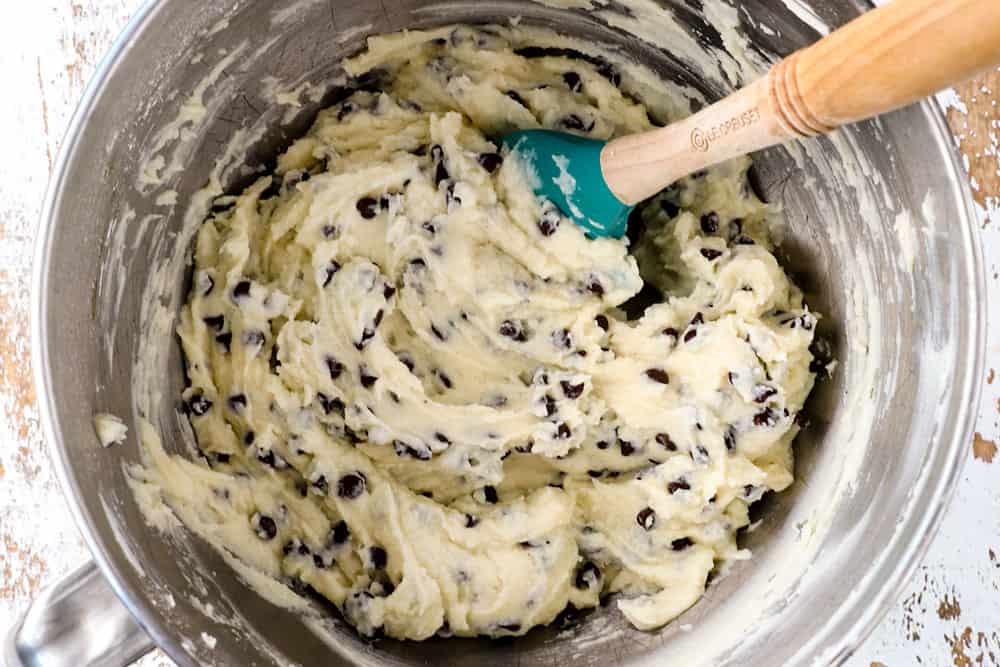 showing how to make cannoli dip recipe by stirring mini chocolate chips into the creamy ricotta/mascarpone dip