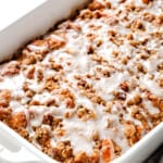 side view of cinnamon roll french toast casserole with icing and pecan topping