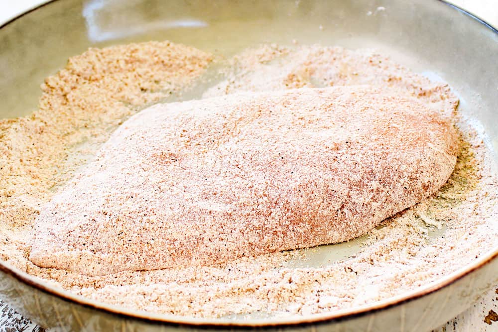 showing how to make garlic chicken recipe by dredging the chicken in flour and seasonings