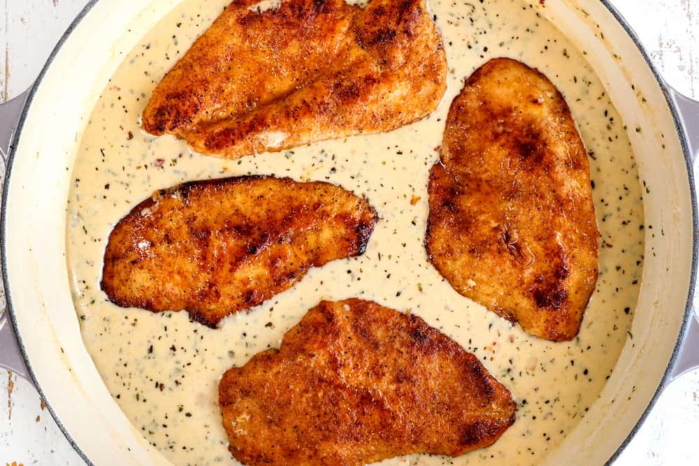 showing how to make garlic chicken recipe by adding seared chicken to creamy Parmesan sauce