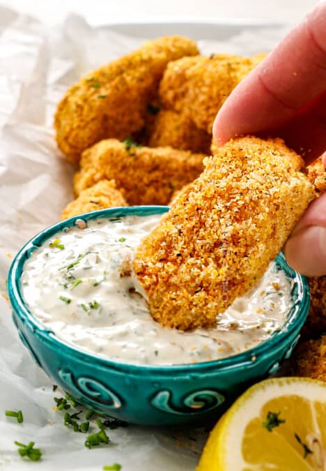 showing how to serve fish sticks by dipping a fish stick in tartar sauce