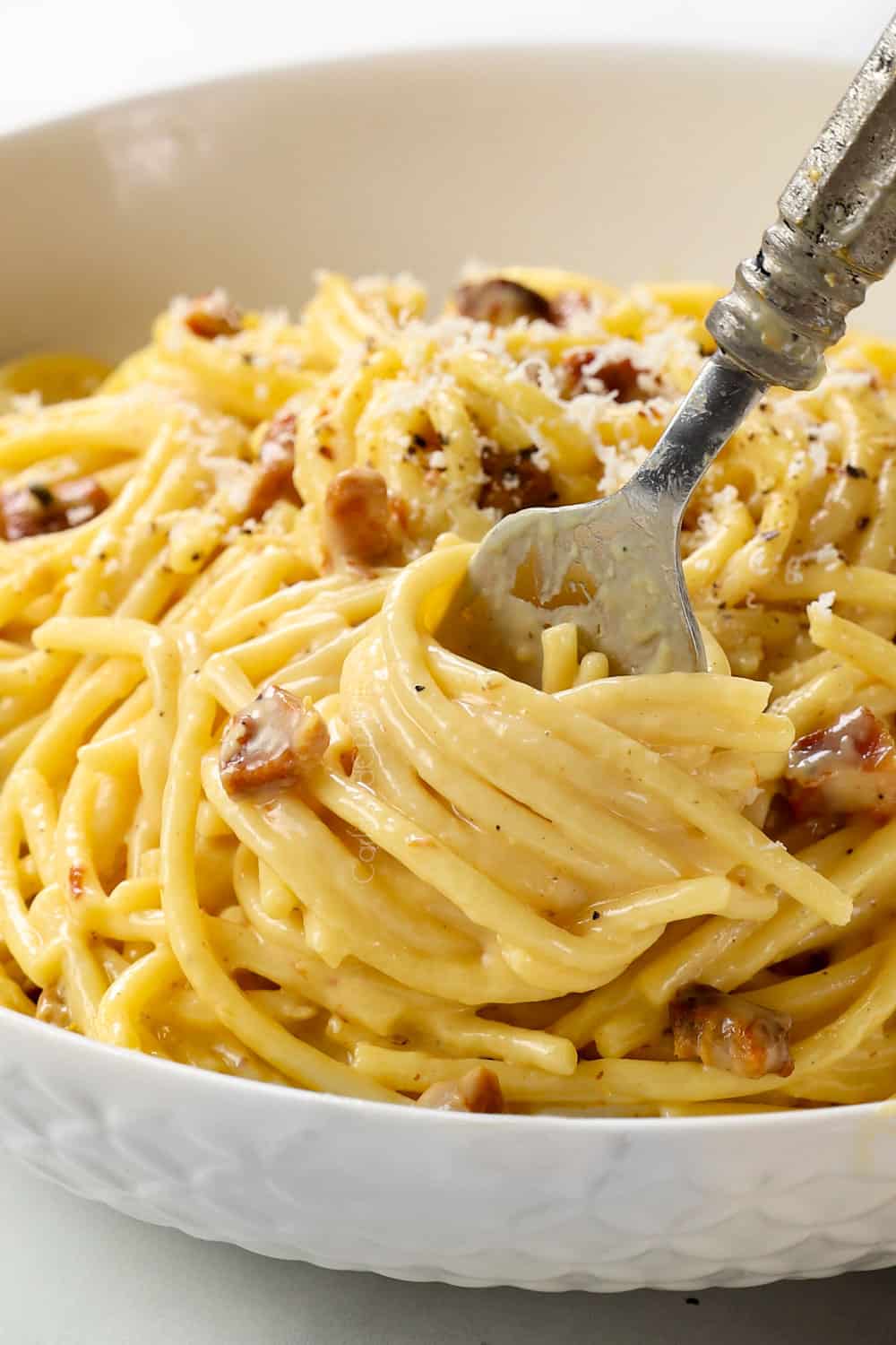 up close of twirling spaghetti Carbonara on a fork showing how creamy it is