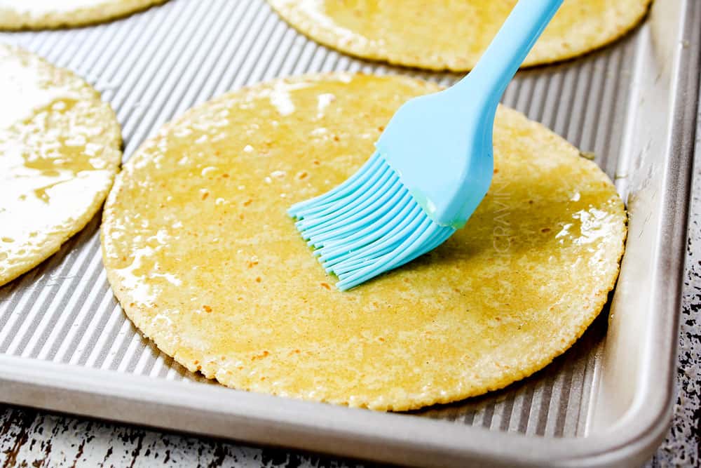showing how to make shredded beef tacos by brushing the corn tortillas with olive oil